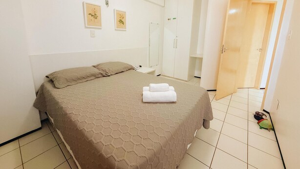 Une chambre à coucher comprenant un lit, une armoire et une porte donnant sur une autre pièce.