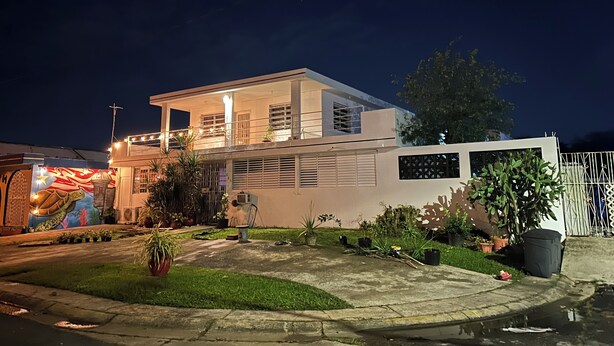 A modern two-story house with a balcony, a small garden, and a security gate. - Exclusive Tropical Oasis: Complete Privacy, Pool, and 24/7 Solar Power (Carolina)