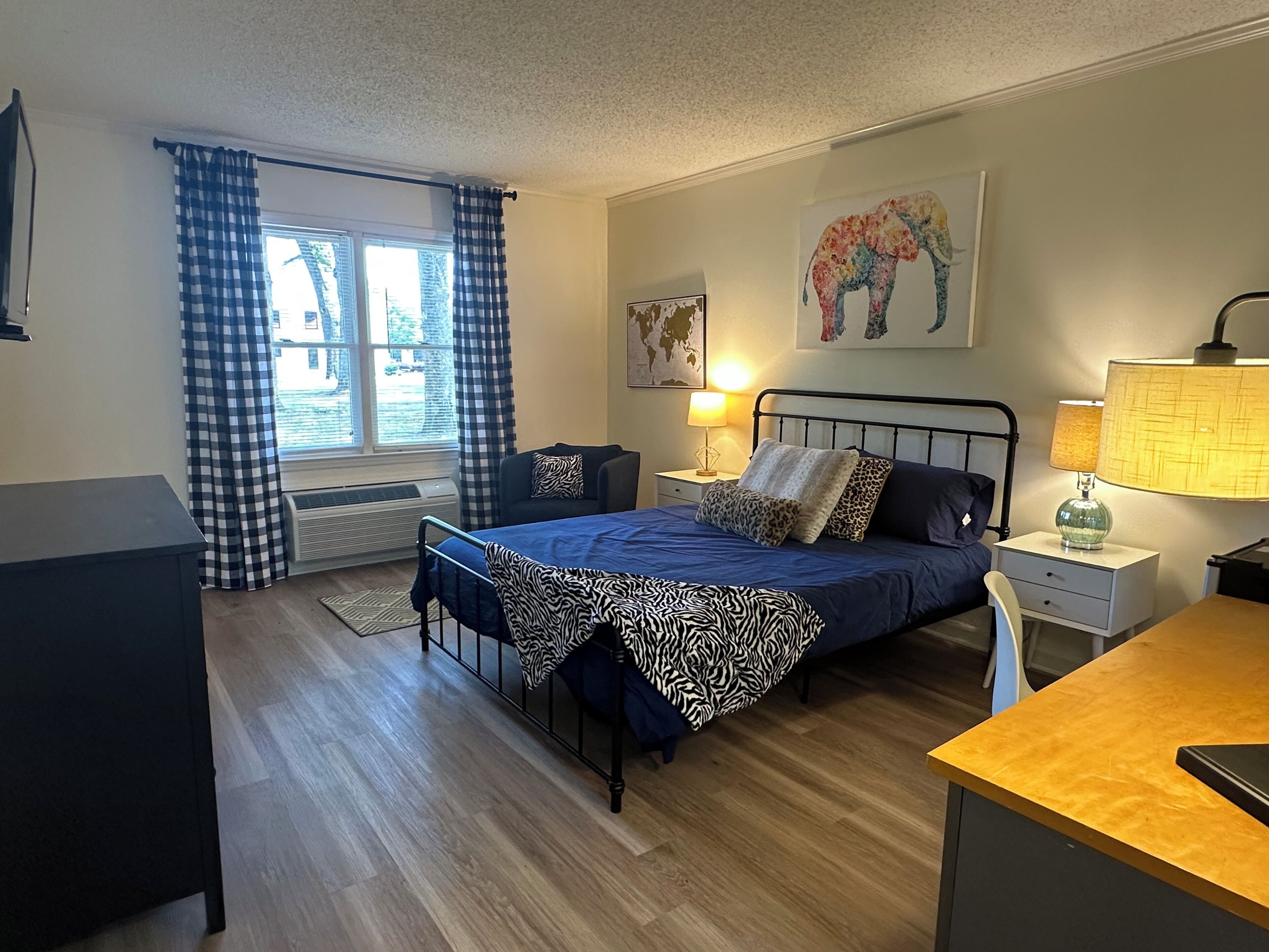A bedroom with a bed, bedside tables, a desk, and a window with curtains.