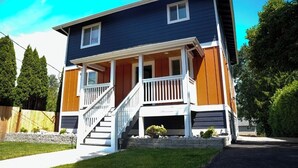 A two-story house with a front porch, a staircase, and a small garden area.