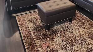 A modern living room with a sectional sofa, ottoman, and patterned rug.