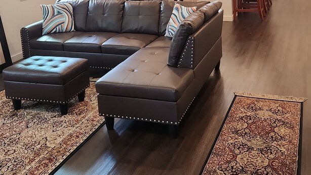 A modern living room with a sectional sofa, ottomans, and a patterned rug.