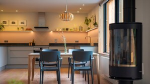 Une cuisine moderne avec un coin repas, comprenant un îlot central, des luminaires suspendus et une grande fenêtre.