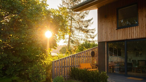 Un bâtiment moderne doté d’une terrasse en bois et d’une entrée en verre.
