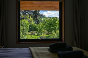 Ein Zimmer mit Fensterblick auf eine dichte, grüne Landschaft.