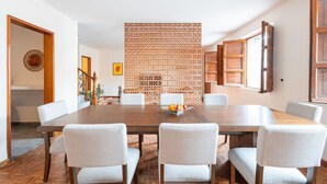Een eethoek met een houten tafel, zes stoelen en een decoratieve scheidingswand.