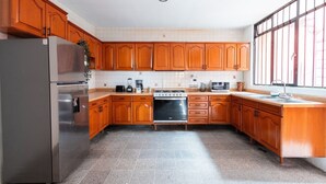 Een keuken met houten kastjes, een roestvrijstalen koelkast, een fornuis en een spoelbak.