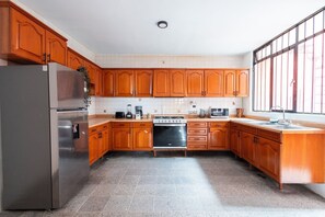 A kitchen with wooden cabinets, a stainless steel refrigerator, a stove, and a sink.