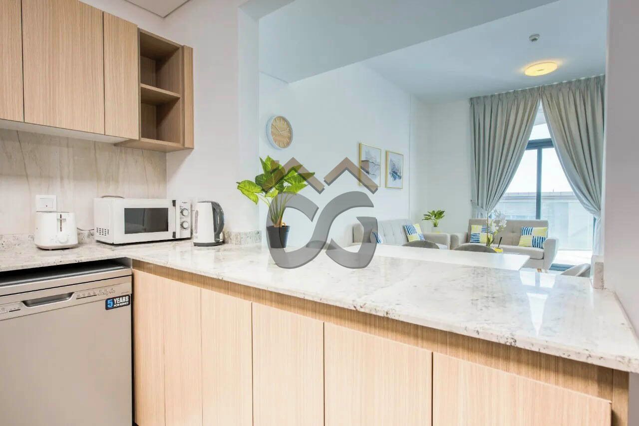 Een moderne keuken met houten kasten, een magnetron, een koffiezetapparaat en een vaatwasser. Er is een zithoek met een bank en een plant.