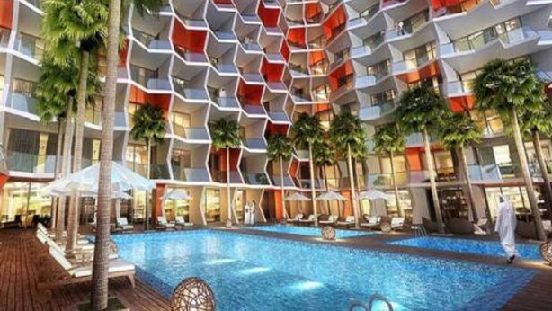 A modern hotel with a pool area, multiple balconies, and palm trees.