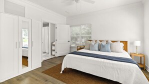 A bedroom with a bed, a ceiling fan, a window with blinds, a nightstand, and a wardrobe. - Beautiful Townhouse IN THE VERY HEART OF DT MT, DORA! (Mount Dora)