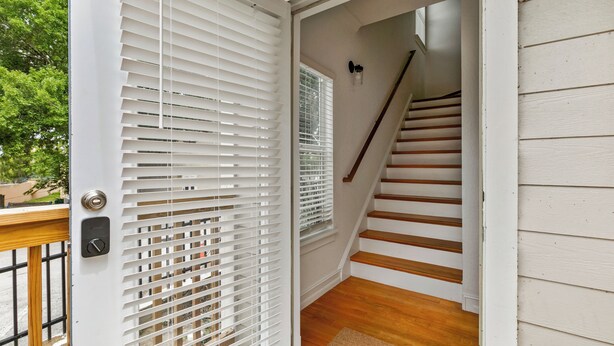 A staircase with white railings and a wooden floor leading to an upper level. - Beautiful Townhouse IN THE VERY HEART OF DT MT, DORA! (Mount Dora)