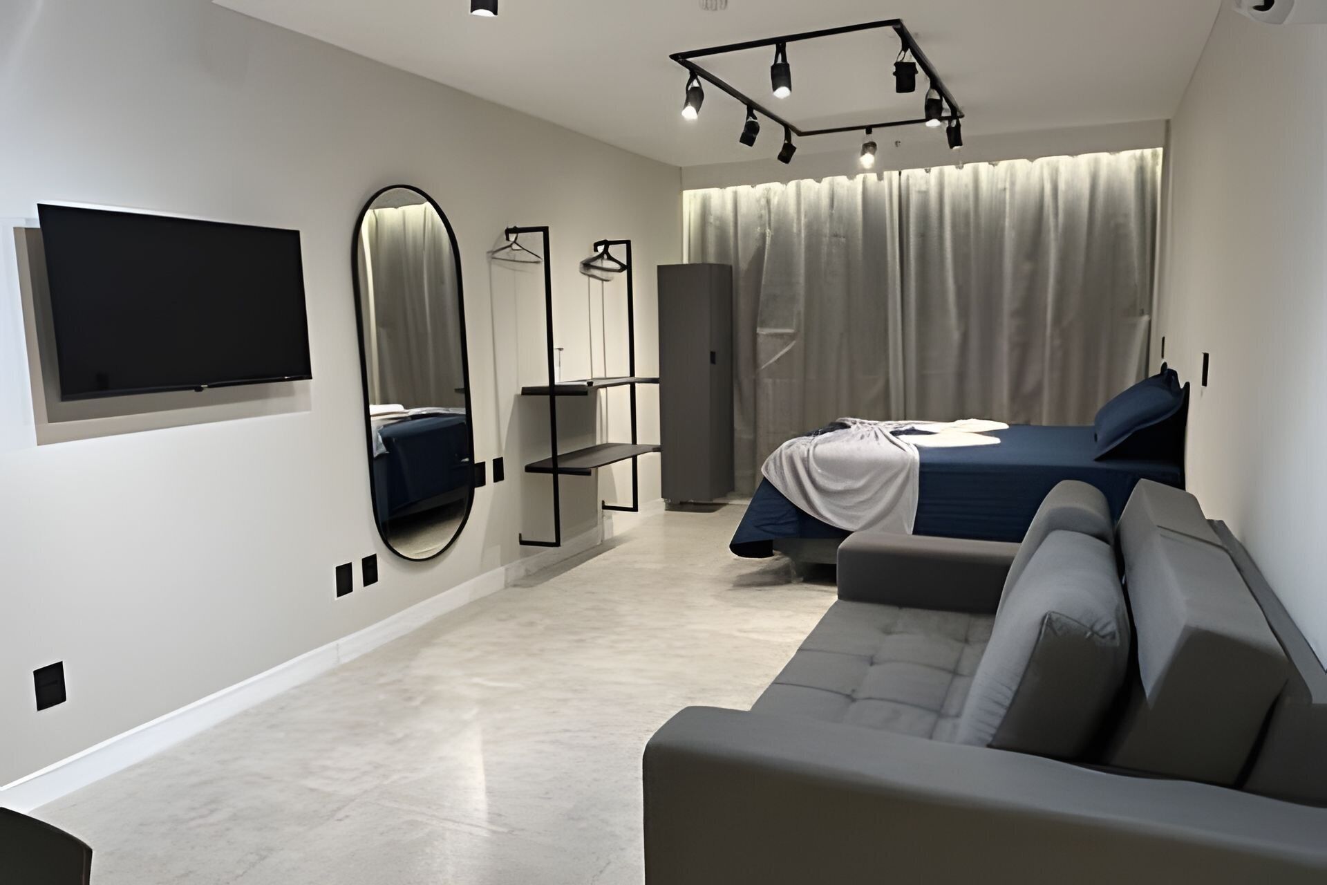 A modern bedroom with a bed, a sofa, a TV, and a mirror.