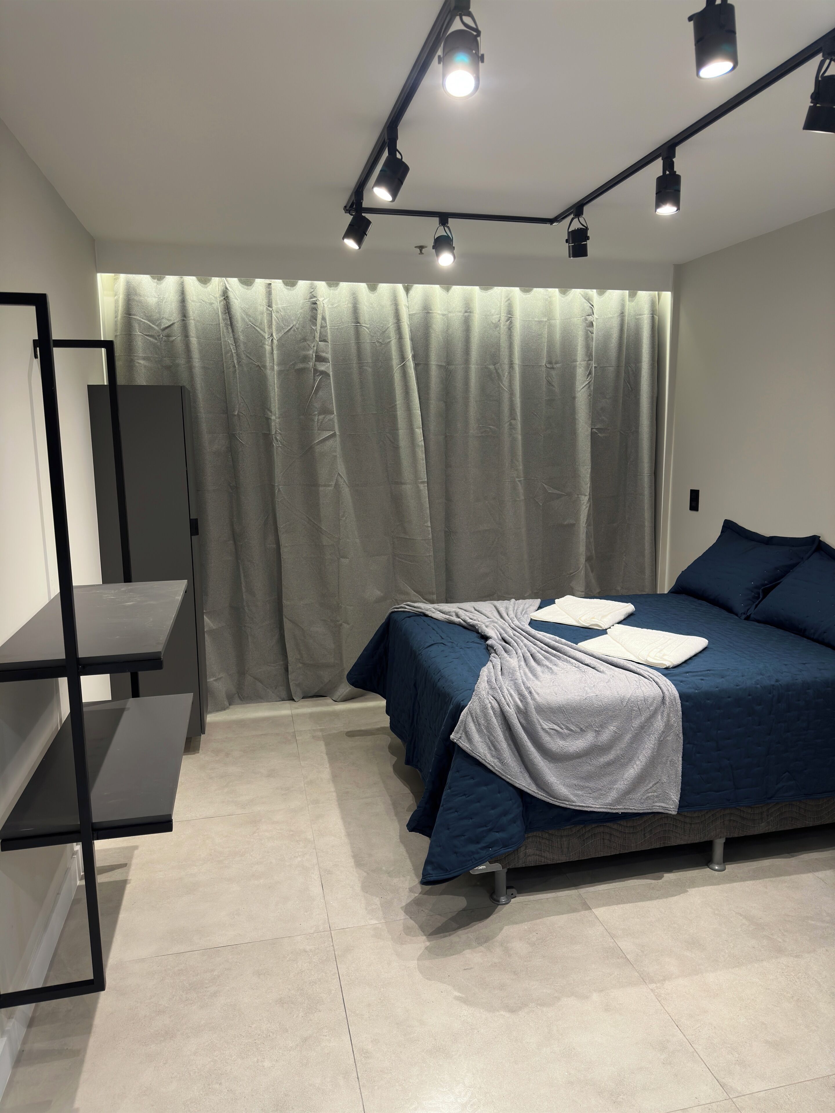 Un dormitorio con cama, escritorio y cortina.