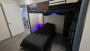A compact room with a bunk bed, a small bedside table with a lamp, and a closet with a ladder. - Cozy and Serene 2-bedroom pet friendly house with AC in Downtown Lorain (Lorain)
