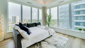 Un dormitorio moderno con una cama grande, vistas a la ciudad y una decoración minimalista.