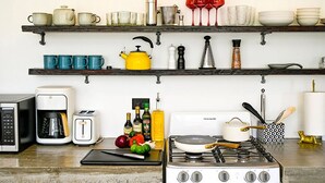 Une cuisine équipée d’une cuisinière, d’une machine à café, d’un grille-pain et de divers ustensiles de cuisine posés sur le plan de travail.