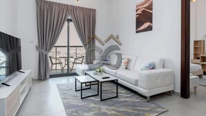 A modern living room with a sofa, coffee table, TV, and a large window with curtains.