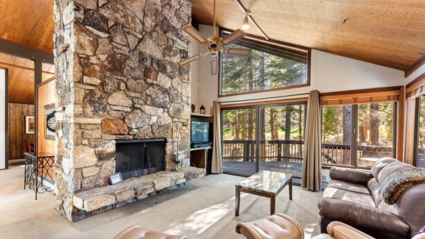 A stone fireplace, leather furniture, and large windows in a spacious living area.