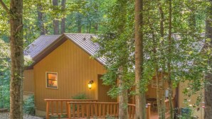 Una baita di legno con un portico, circondata da alberi.