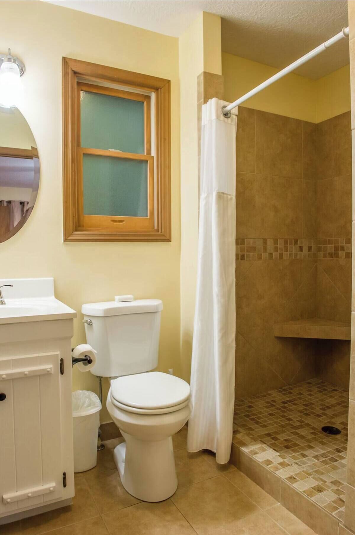 A bathroom with a toilet, sink, and shower area.
