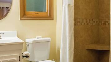 A bathroom with a toilet, sink, and shower area.