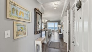 A hallway with a dining area, a large mirror, and artwork on the walls. - Ocean Place 22 - Sea Forever (Fernandina Beach)