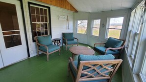 Een overdekt terras met houten meubels en een groene vloer.