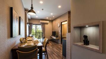 Uma sala de jantar com uma mesa posta para dois, uma luminária pendente e uma prateleira na parede com um objeto decorativo.