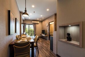 Un comedor con una mesa dispuesta para dos, una lámpara colgante y un estante de pared con un objeto decorativo.