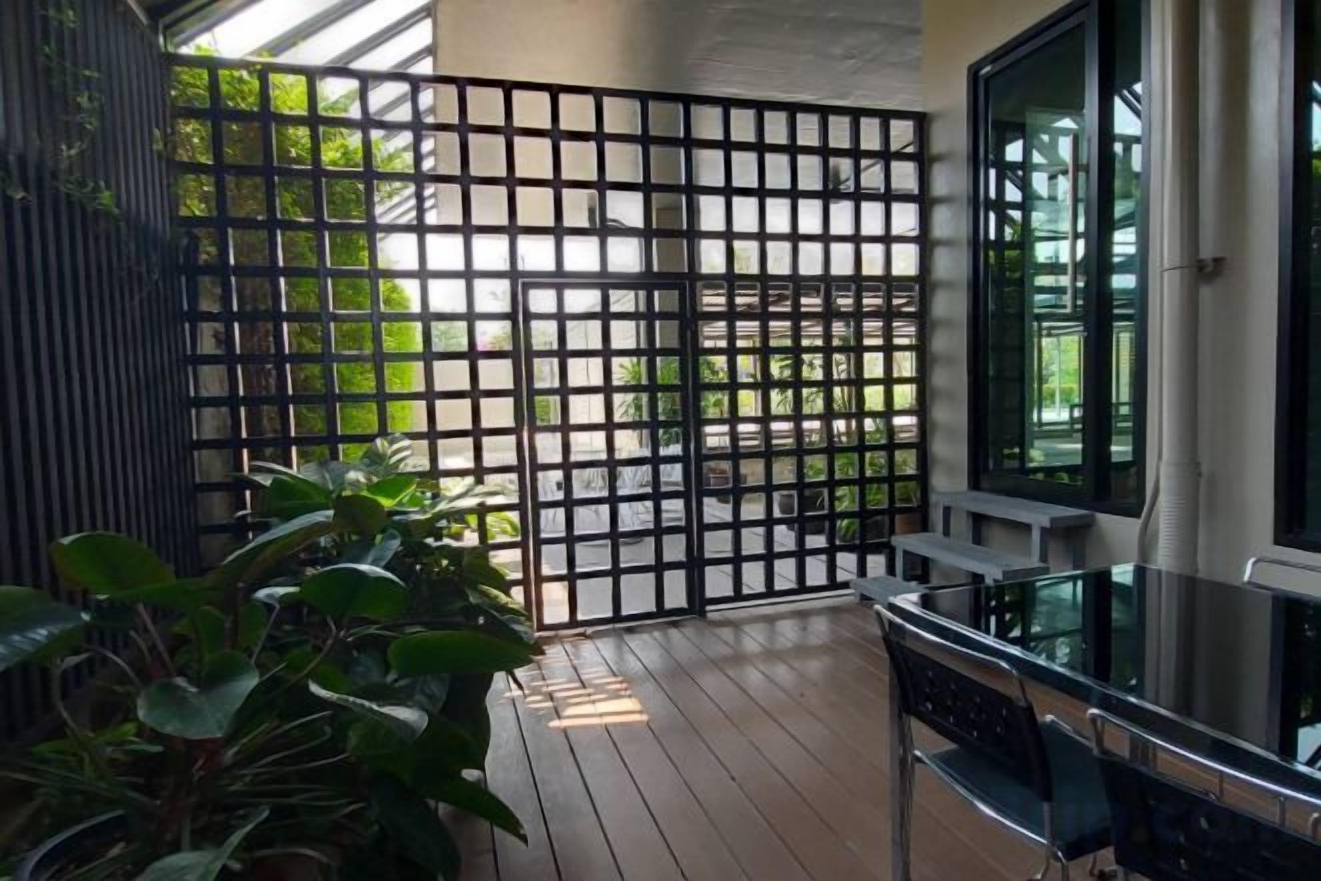 A balcony with a wooden floor, a metal fence, and a glass table.