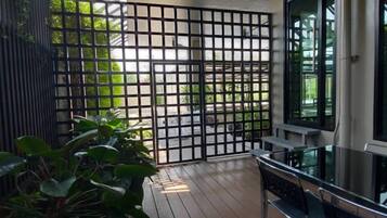 A balcony with a wooden floor, a metal fence, and a glass table.
