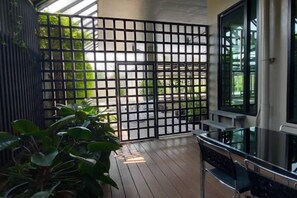 Un balcon doté d’un plancher en bois, d’une rambarde en métal et d’une table en verre.