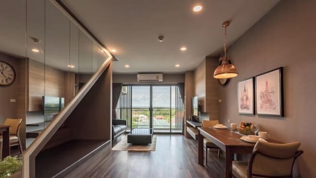 Una habitación de hotel moderna con piso de madera, una escalera, un comedor y un ventanal con vistas.