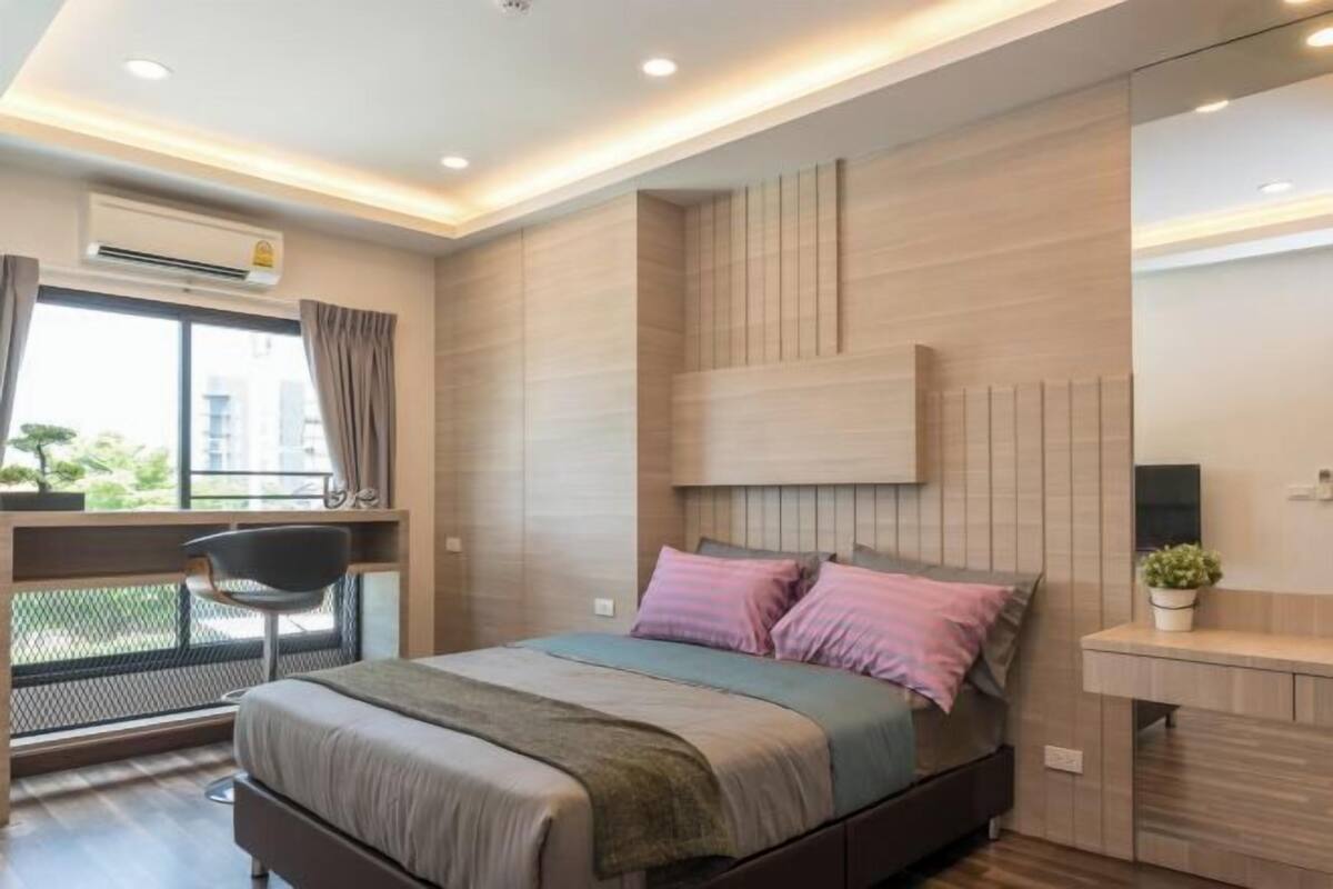Une chambre moderne avec un lit, une table de chevet et un espace bureau.