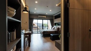 Una habitación de hotel moderna con cama, zona de comedor y vistas amplias a través de grandes ventanales.