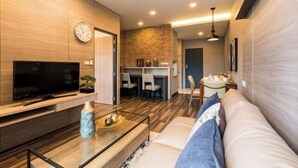 Una sala de estar moderna con un televisor de pantalla plana, una mesa de centro, un sofá y un comedor con sillas y una mesa.