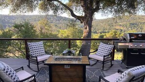 A deck with outdoor furniture, a grill, and a view of a forested landscape. - Rough & Ready Ranch Retreat- 4 bed/3 bath home w/ gorgeous views (Rough and Ready)