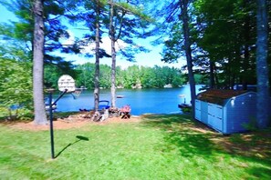 A lakeside property with a dock, a shed, and a lawn.