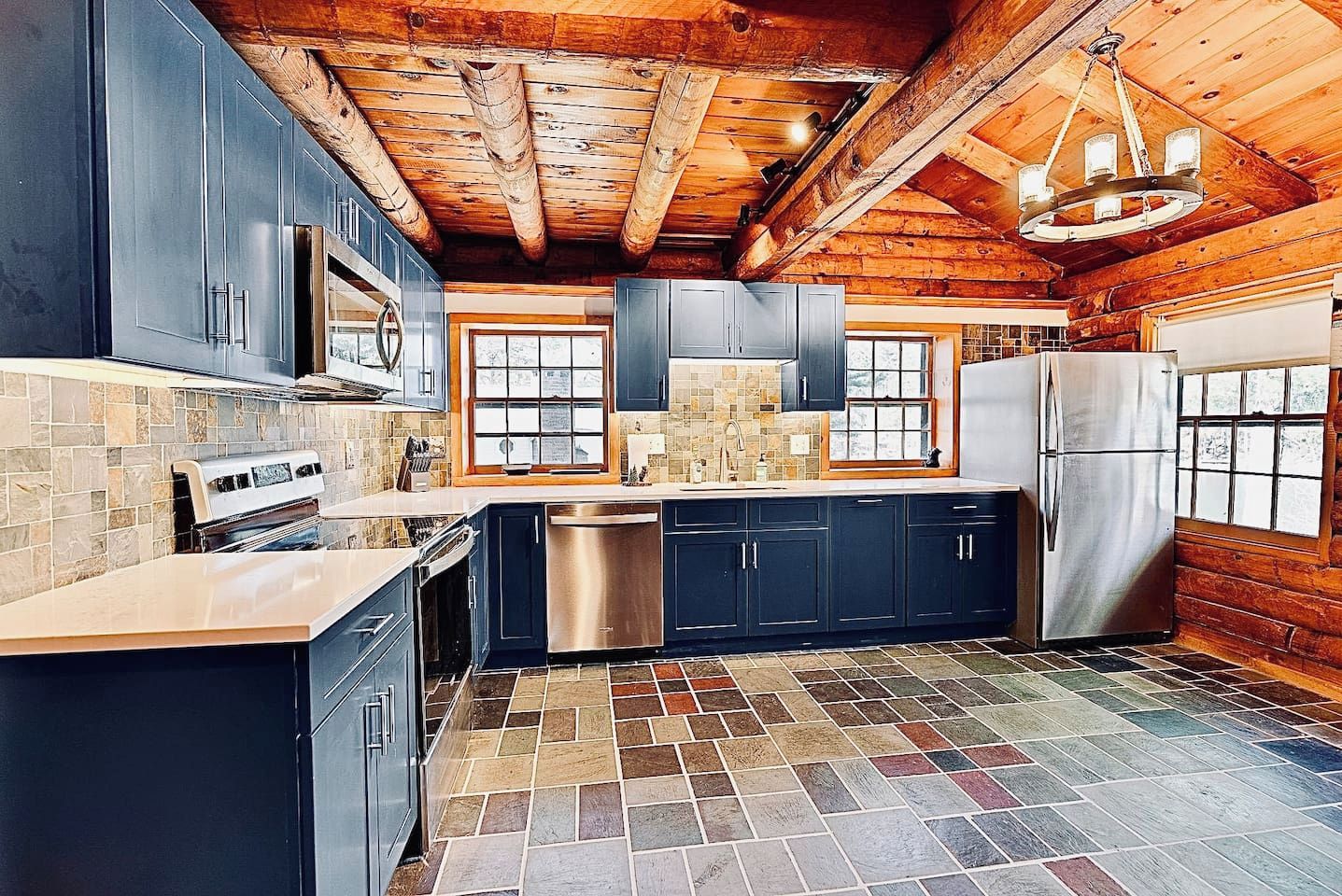 A kitchen with dark cabinets, a stainless steel refrigerator, and a tiled floor.