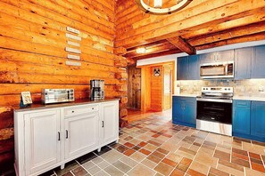Eine Küchenzeile im Blockhausstil mit Holzwänden, gefliestem Boden und modernen Geräten.