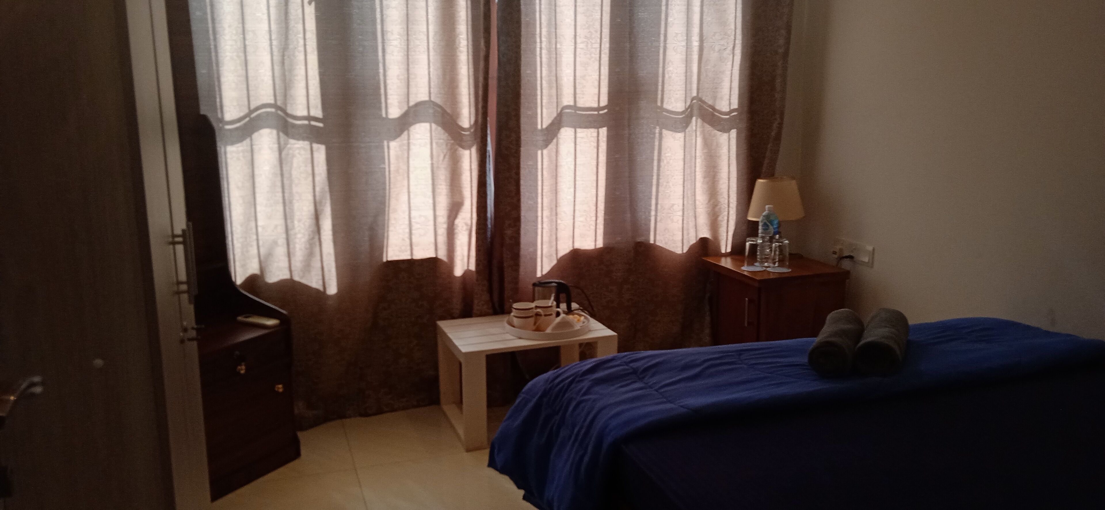 A bedroom with a bed, a small table with a lamp, and a chair.
