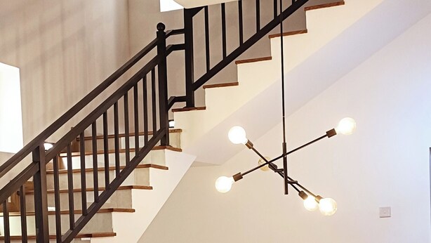 A dining area with a wooden table and chairs, a staircase with black railings, and a modern chandelier with multiple bulbs. - Sweet Home Ja-Ela (Ja-Ela)