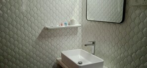 A bathroom with a white hexagonal tile backsplash, a white sink, and a mirror above the mirror. - Sweet Home Ja-Ela (Ja-Ela)