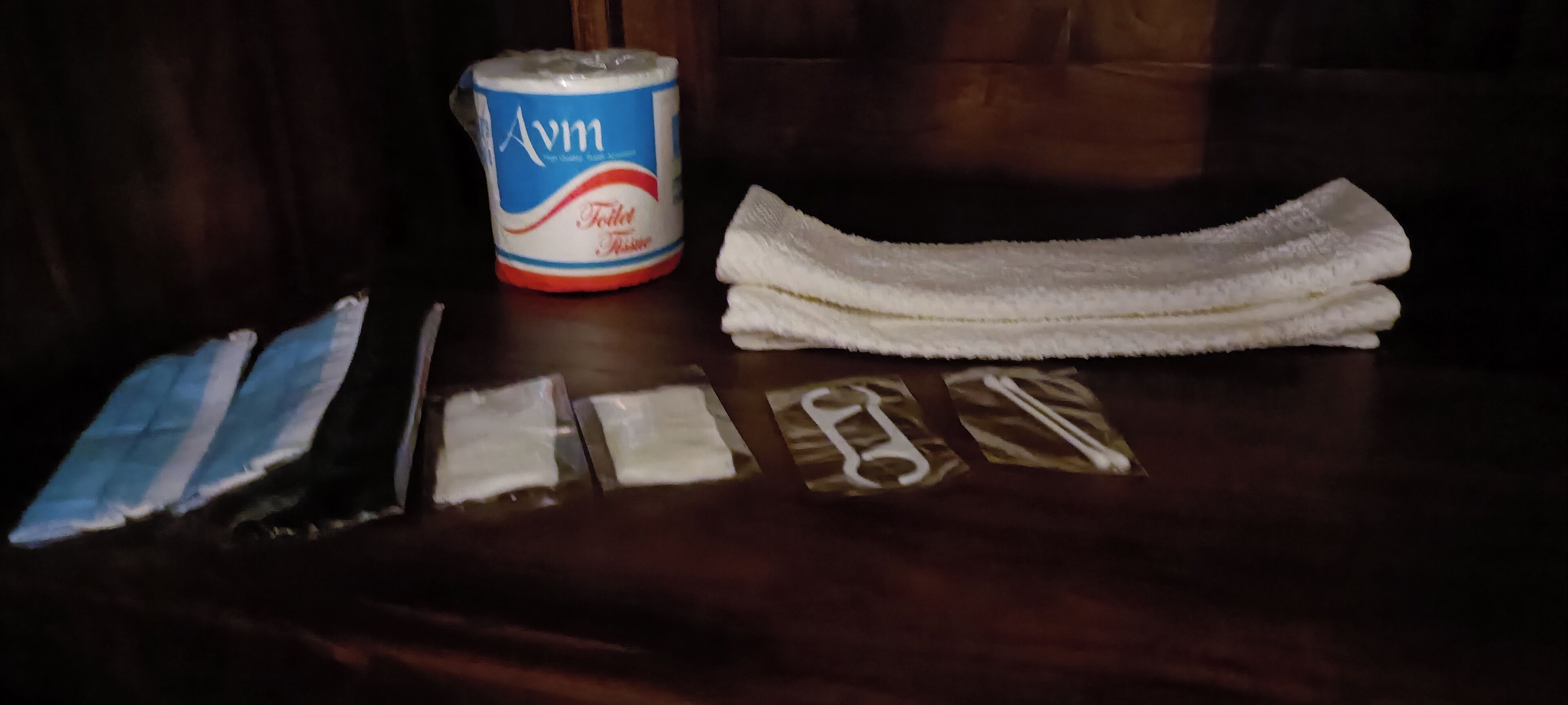 A table with a package of Avm toilet paper, a white towel, and a few other items.