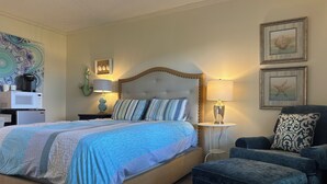 A neatly arranged bedroom with a bed, bedside tables, a chair, and a small table.