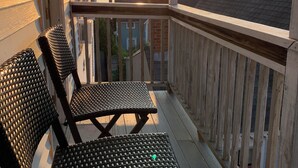 A wooden deck with two wicker chairs and a railing overlooking a body of water. - Cozy 2-Bed Lakefront Weirs Beach (Laconia)