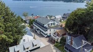 A residential area with houses, a large building with a sloped roof, and a body of water in the background. - Cozy 2-Bed Lakefront Weirs Beach (Laconia)