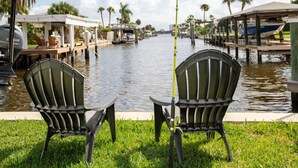 Two Adirondack chairs facing a waterfront with a boat docked on the right. - Riverside Retreat w Fireplace (Daytona Beach)