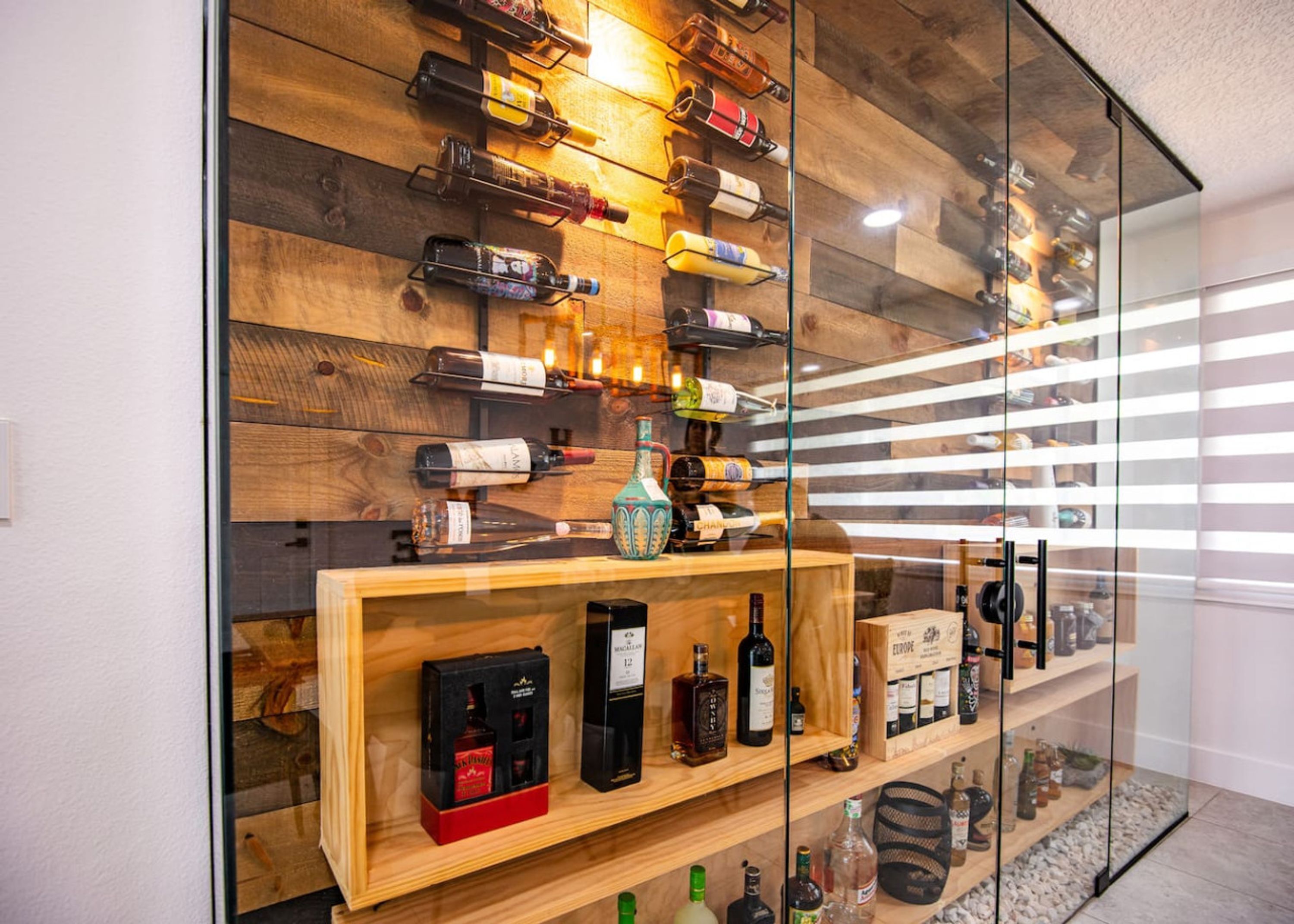 Un meuble à bouteilles contenant diverses sortes de vins et une étagère en bois avec des articles emballés.